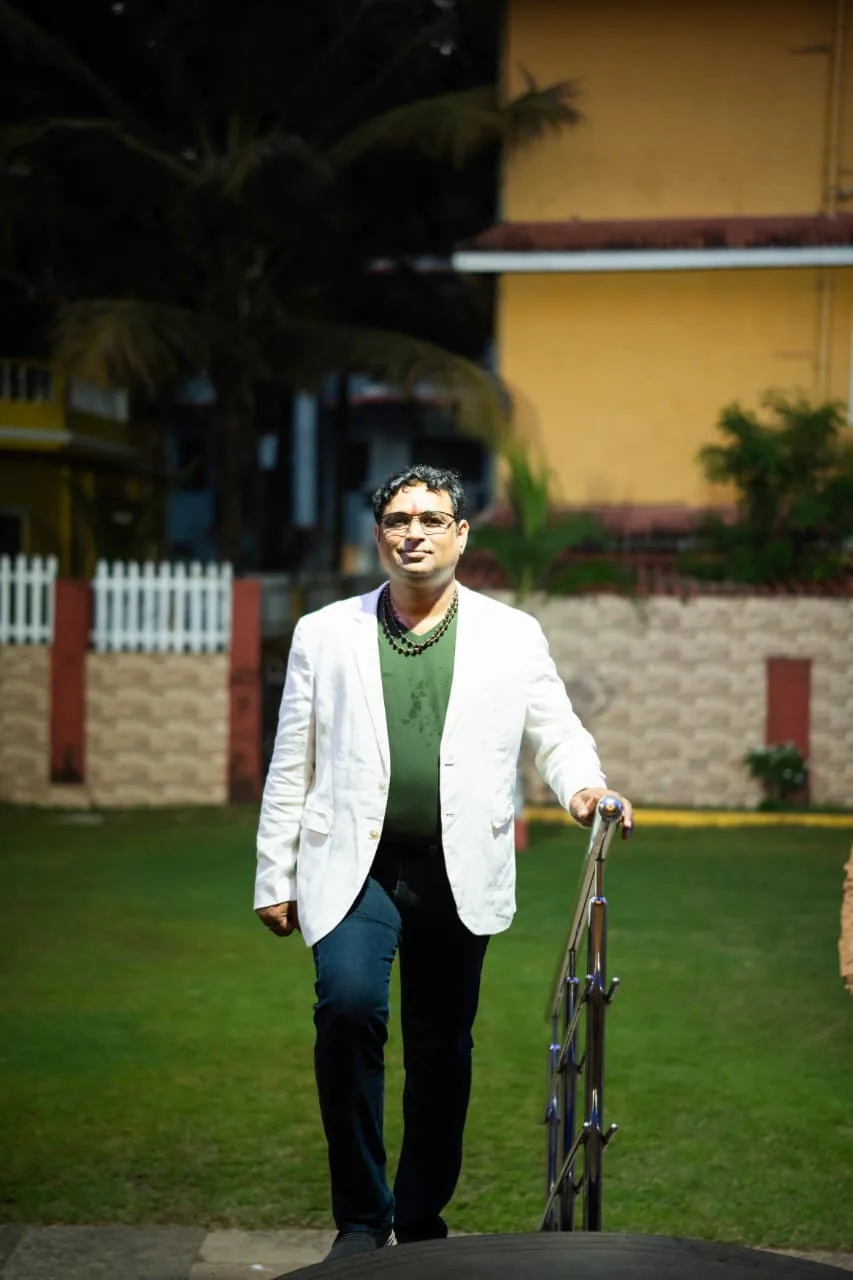 Prakash Shastry Somanchi in a white blazer walking up garden steps